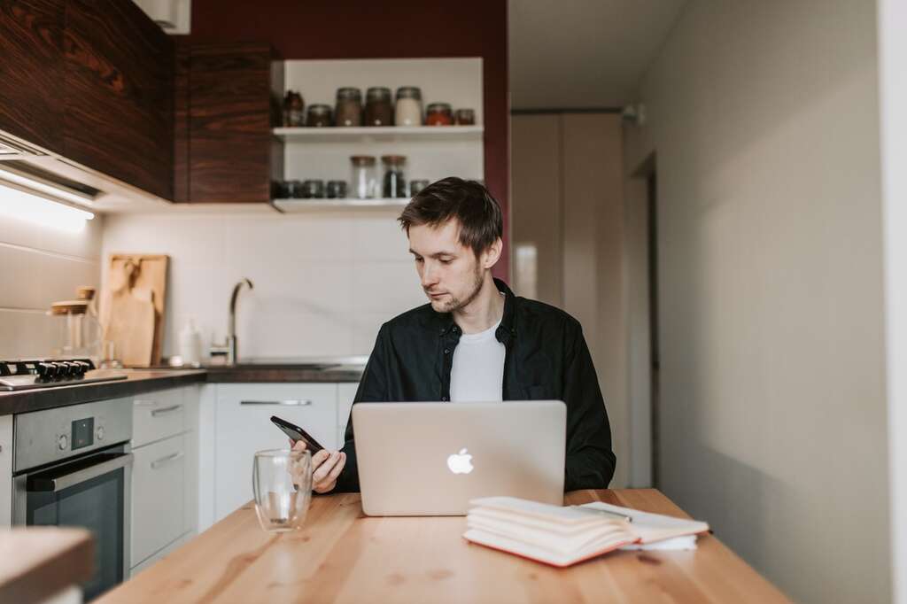 man looking at phone sitting at table