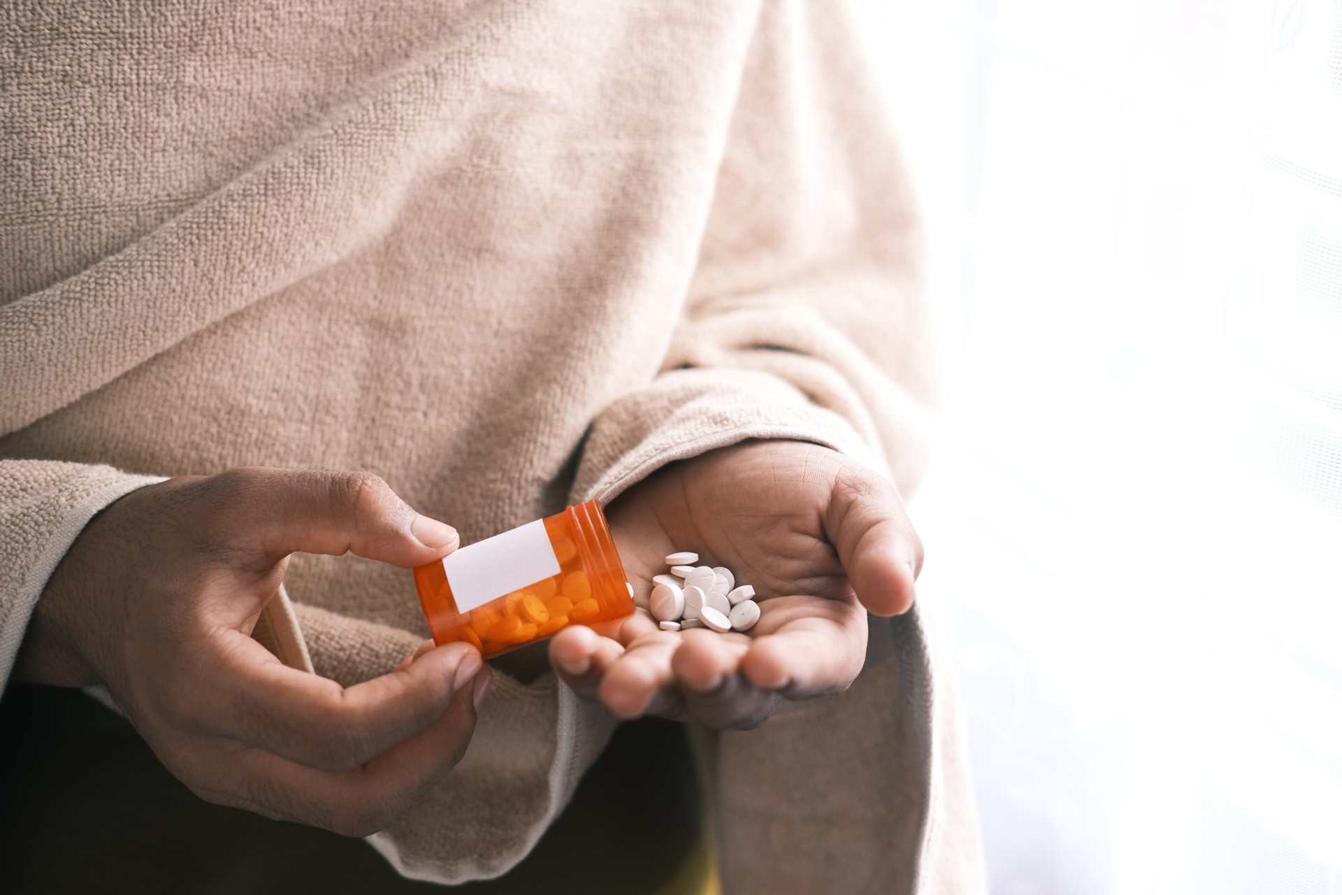 Person pouring prescription medication pills into hand