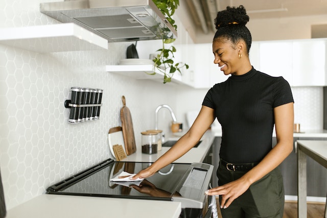 woman cleaning the stovetop at home