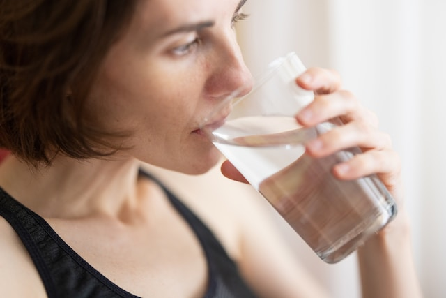 Woman drinking water for urine sample collection