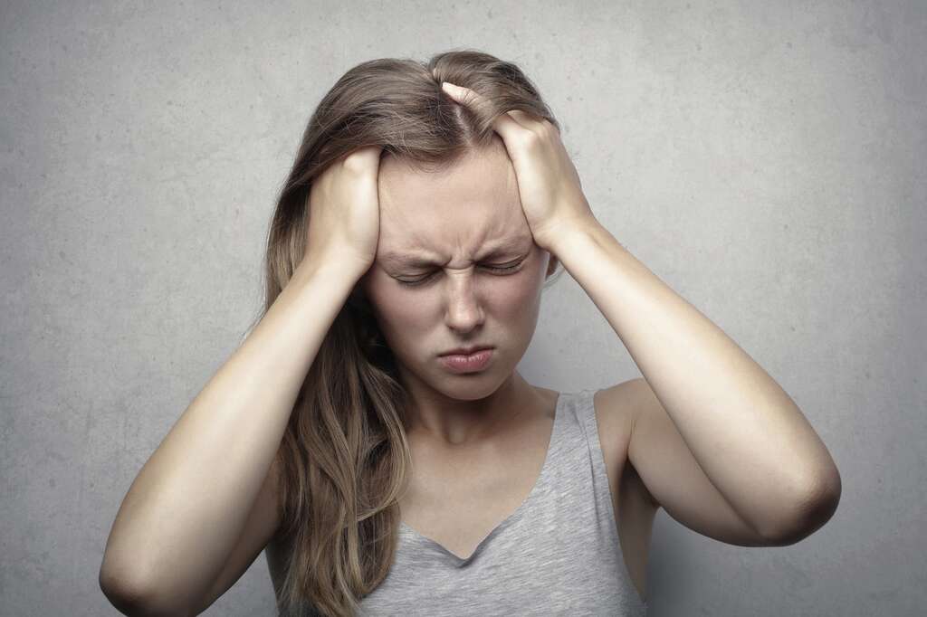 woman holding head in pain with a headache