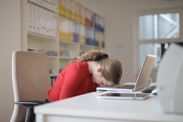 woman resting her head on her laptop