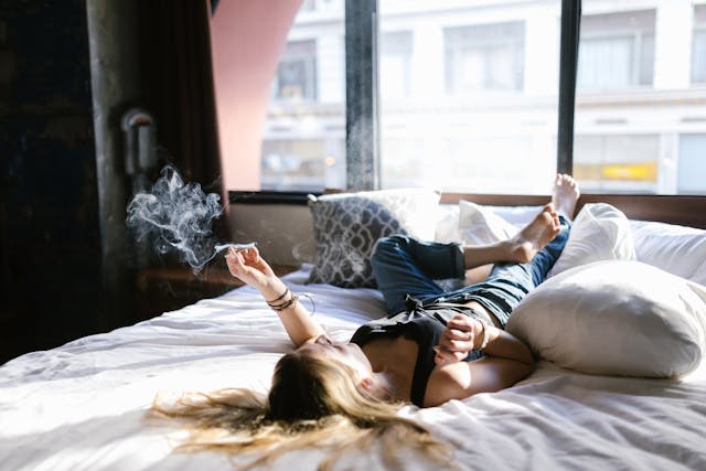 Woman smoking recreational marijuana in bed