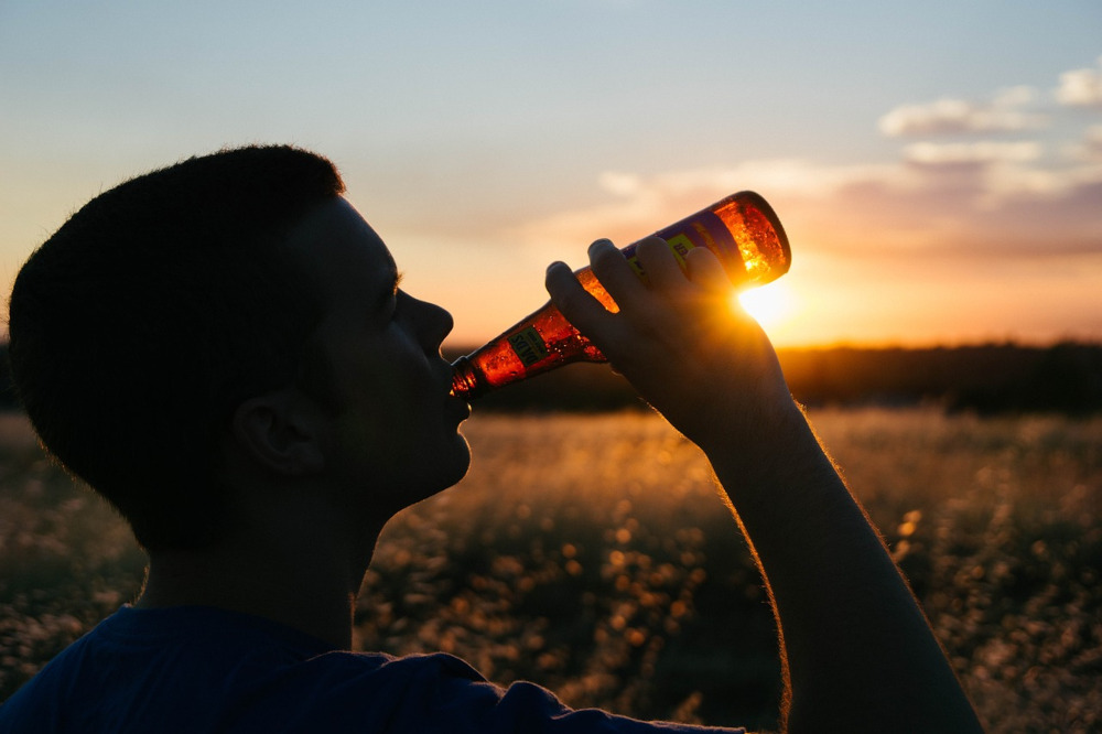 Person drinking from a beer bottle