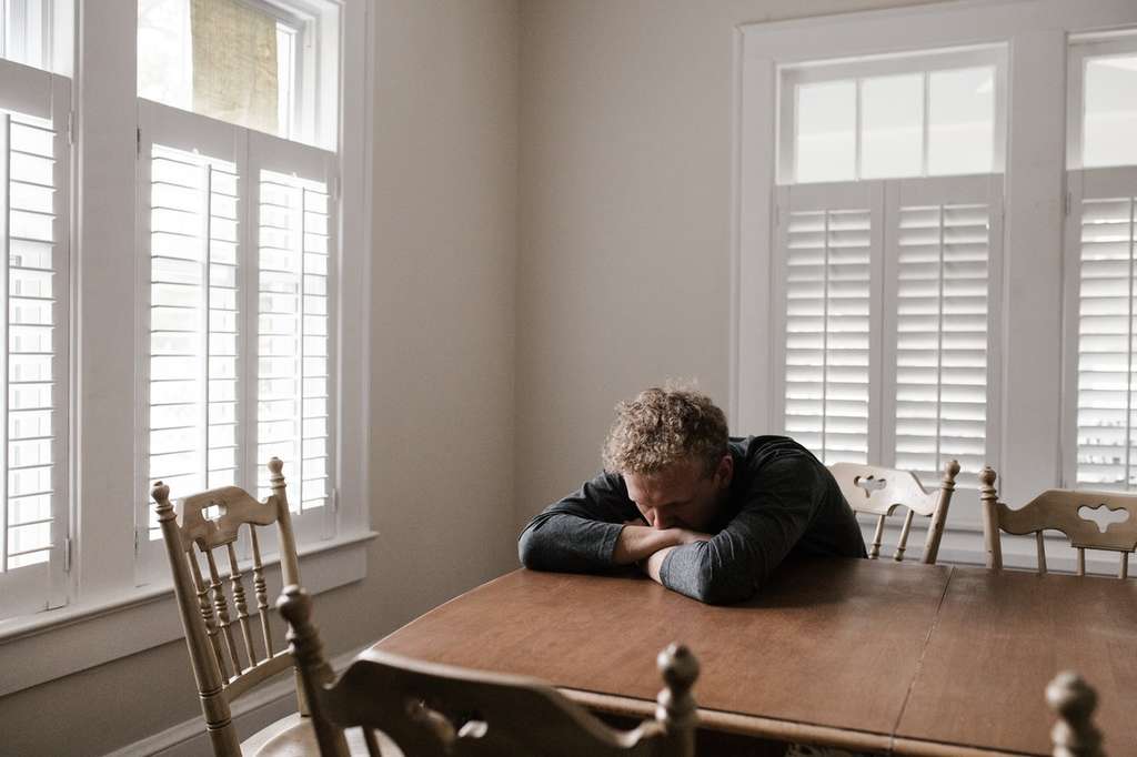 A distressed man sitting at a dining table