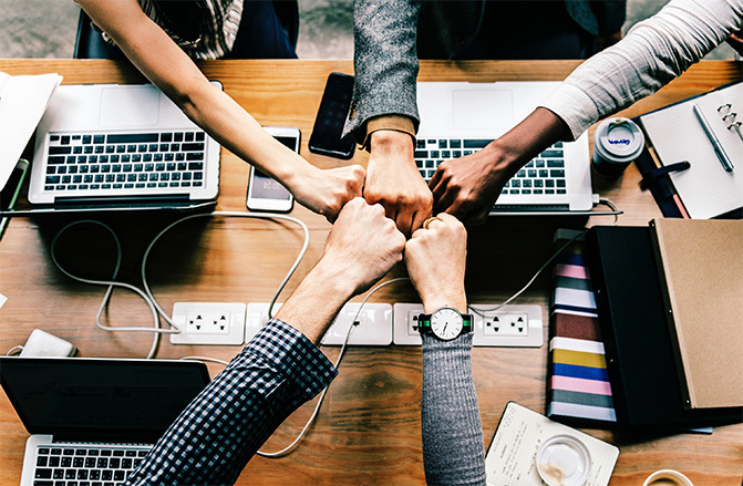 employees putting hands it at the table with computers