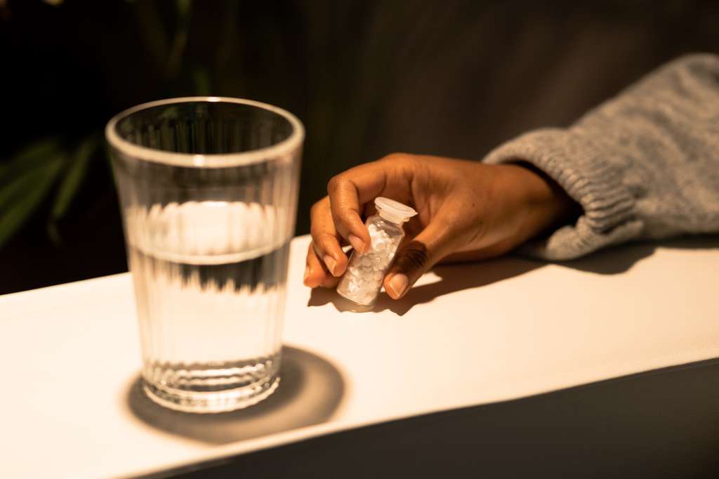 A person holding a bottle of white amphetamine pills