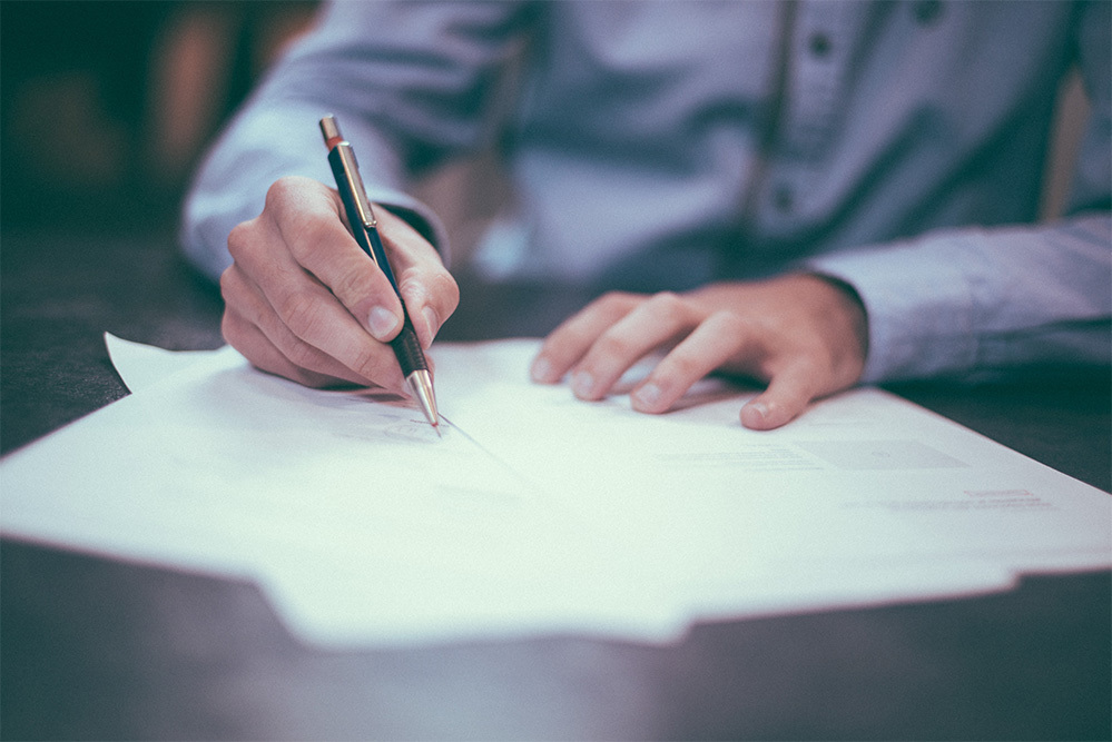 man writing on paper at work