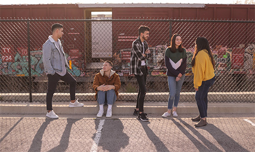 teenagers hanging out against fence