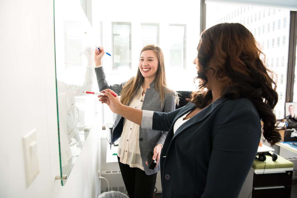 Two women smiling and laughing in the workplace