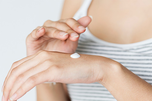 woman rubbing lotion on hand