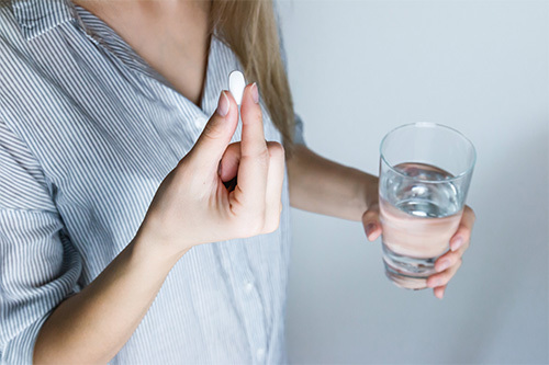 woman taking pill with water