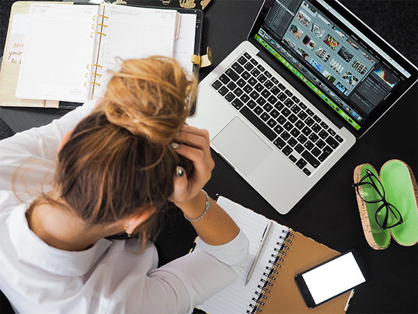 woman with head in hands at her computer